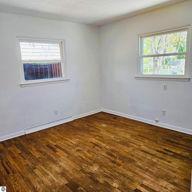 unfurnished room featuring a baseboard heating unit, baseboards, and dark wood-style floors