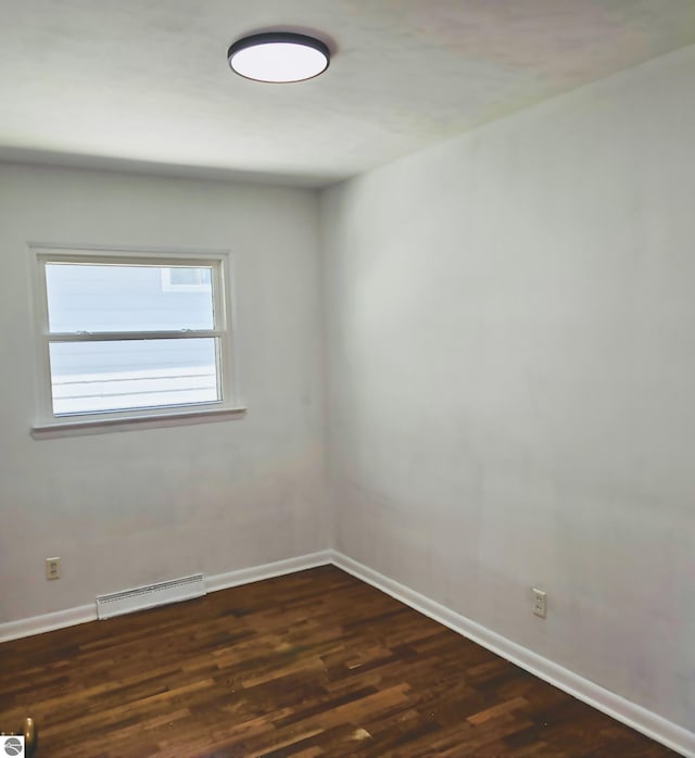 unfurnished room featuring baseboards, visible vents, and dark wood-type flooring