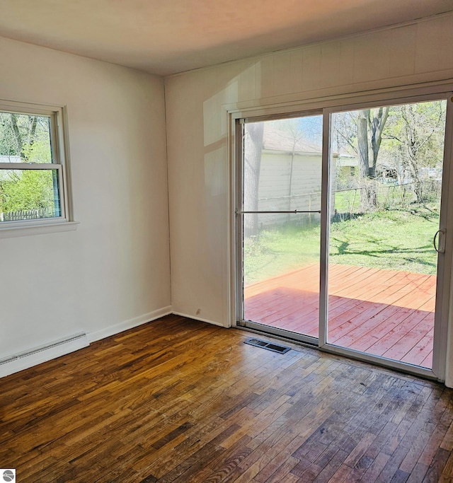 unfurnished room with baseboards, dark wood-type flooring, visible vents, and a baseboard heating unit