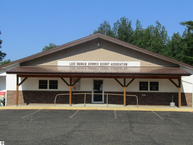 view of front facade featuring metal roof, brick siding, and uncovered parking