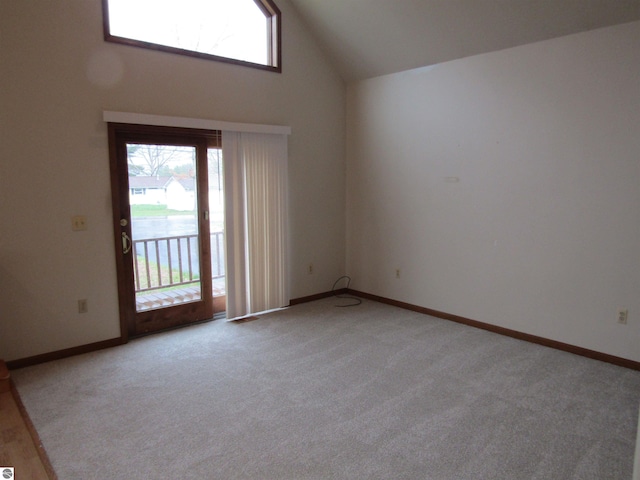 empty room featuring light colored carpet, baseboards, high vaulted ceiling, and a healthy amount of sunlight