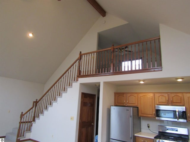 stairs featuring ceiling fan, beamed ceiling, and high vaulted ceiling