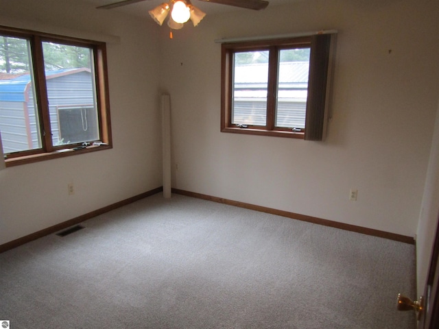 spare room featuring a wealth of natural light, carpet floors, a ceiling fan, and visible vents