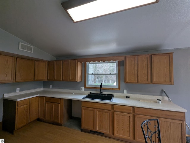 kitchen featuring a sink, brown cabinetry, visible vents, and light wood-style floors