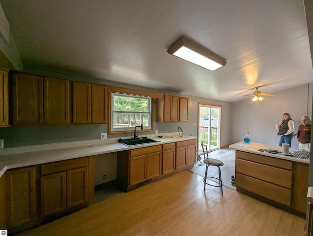kitchen featuring brown cabinetry, light countertops, light wood-style flooring, and a sink