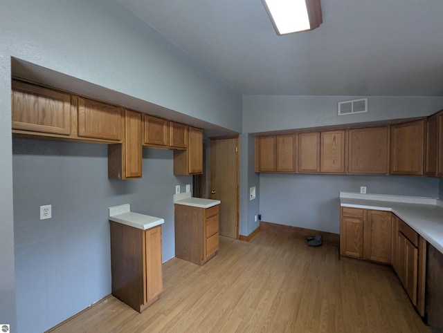 kitchen featuring brown cabinets, built in desk, and visible vents