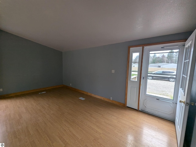 entrance foyer with baseboards, light wood-style floors, and visible vents