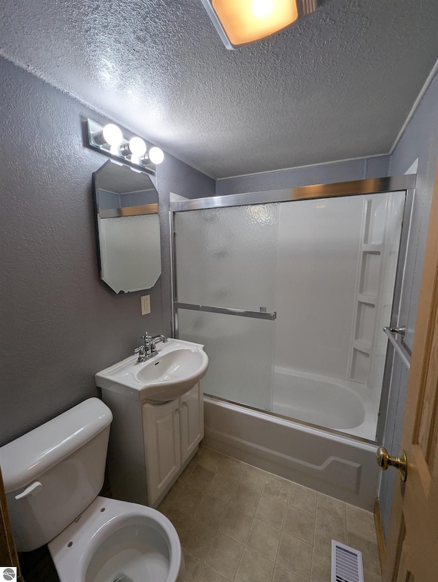 bathroom with toilet, vanity, visible vents, tile patterned flooring, and bath / shower combo with glass door