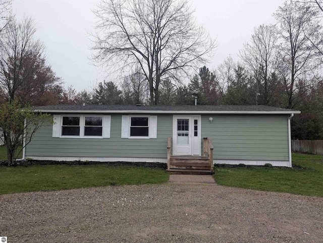 view of front of house featuring a front lawn, roof with shingles, and fence