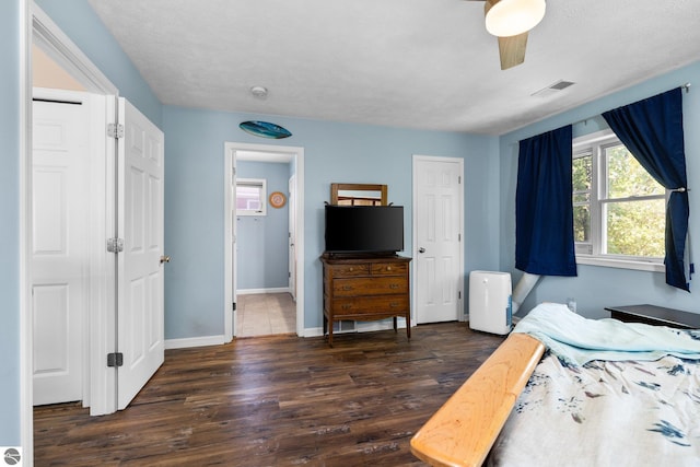 bedroom featuring baseboards, ceiling fan, visible vents, and wood finished floors