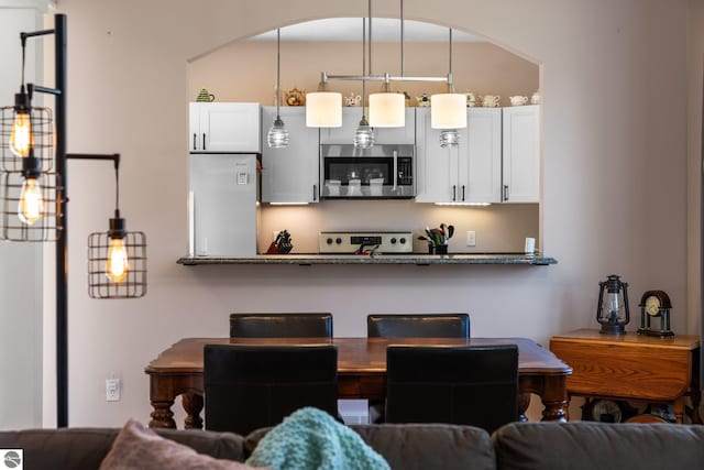 kitchen with stove, open floor plan, refrigerator, and stainless steel microwave