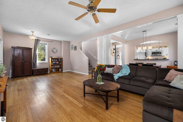 living area featuring light wood finished floors, stairway, baseboards, and ceiling fan