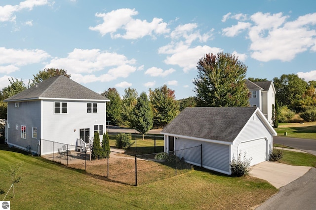 view of property exterior featuring a detached garage, fence, an outdoor structure, a yard, and a shingled roof