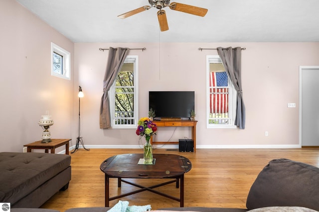 living room featuring ceiling fan, baseboards, and wood finished floors