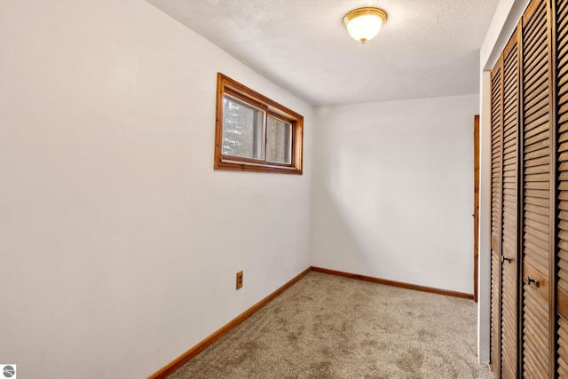 unfurnished bedroom with baseboards, carpet flooring, and a closet