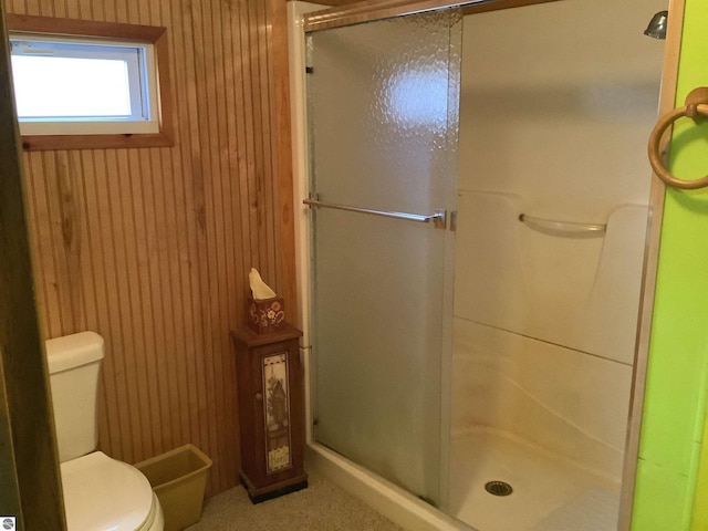 full bathroom featuring a shower stall, wooden walls, and toilet