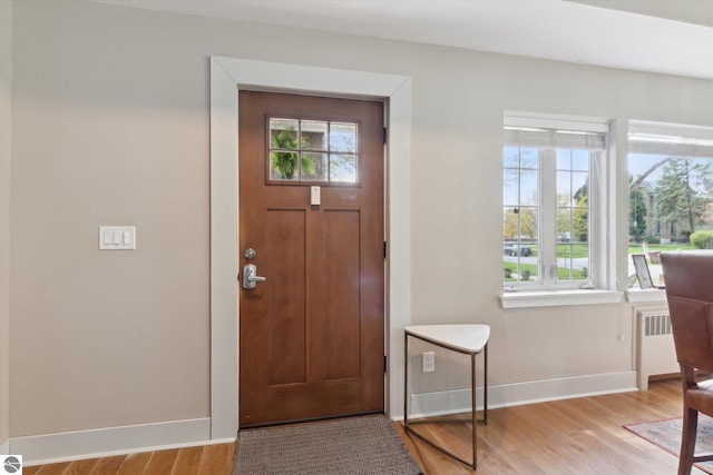 foyer with baseboards, radiator, and light wood finished floors