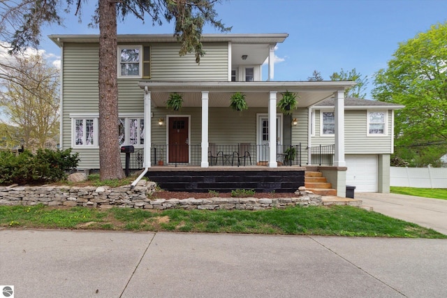 traditional-style house featuring concrete driveway, covered porch, and an attached garage