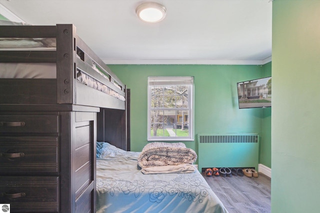 bedroom featuring baseboards, radiator heating unit, crown molding, and wood finished floors
