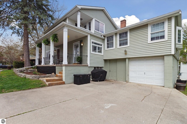 view of front of house with a chimney, covered porch, an attached garage, and concrete driveway