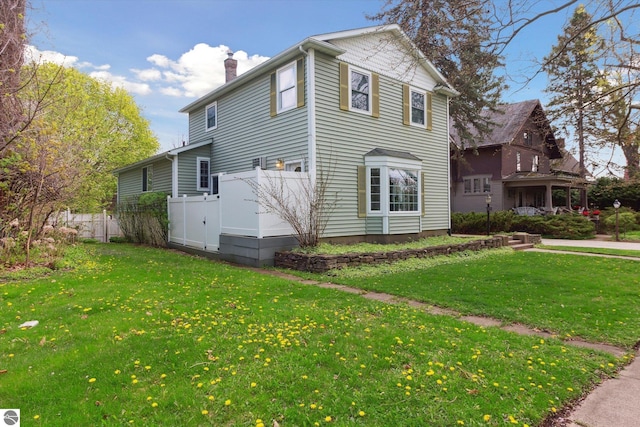 view of side of home featuring a yard, fence, and a chimney
