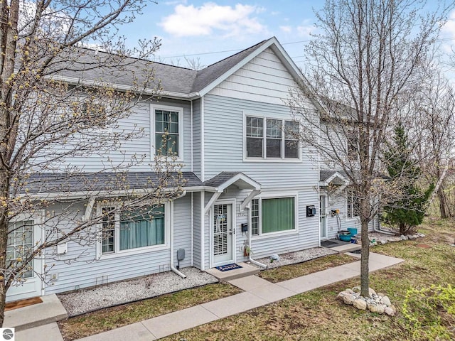 715 Lake Ave Unit 17-C, Traverse City, MI 49684 - traditional home featuring a shingled roof and a front yard