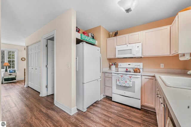 715 Lake Ave Unit 17-C, Traverse City, MI 49684 - kitchen with baseboards, white appliances, a sink, wood finished floors, and light countertops