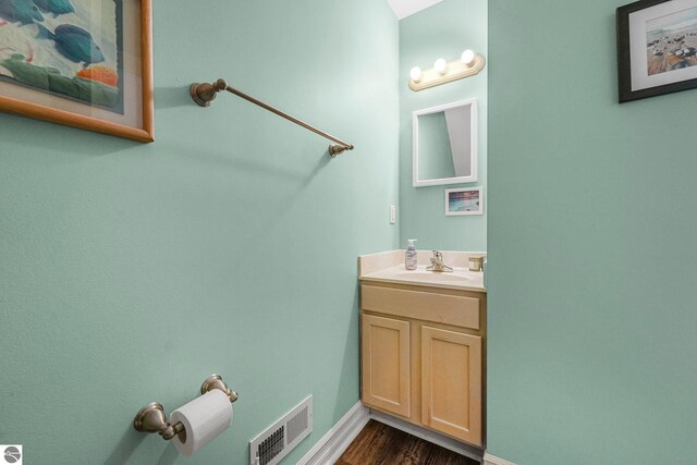 715 Lake Ave Unit 17-C, Traverse City, MI 49684 - bathroom featuring baseboards, vanity, visible vents, and wood finished floors
