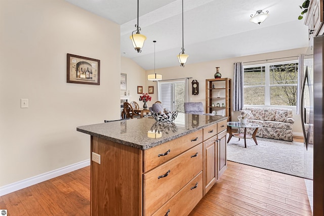 4620 Black Bear Dr Unit 49, Traverse City, MI 49685 - kitchen with freestanding refrigerator, a center island, baseboards, dark stone countertops, and light wood-style floors