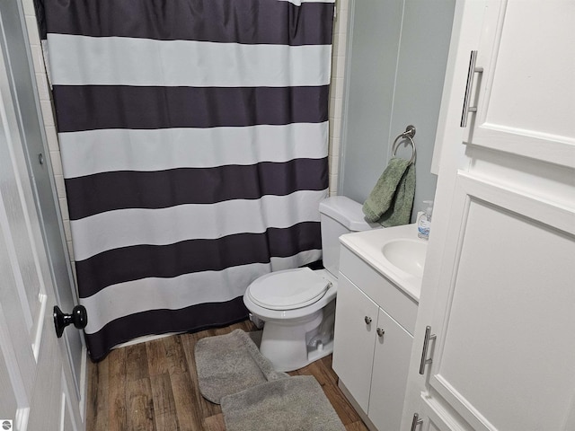 bathroom featuring toilet, curtained shower, vanity, and wood finished floors