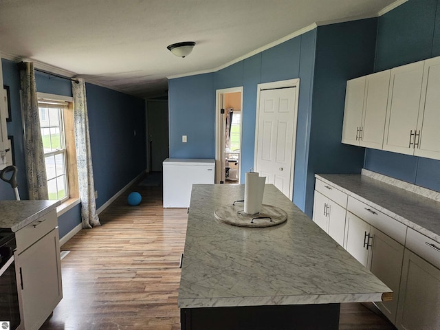 kitchen with a center island, refrigerator, crown molding, wood finished floors, and white cabinets