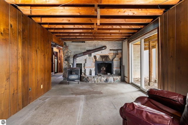 8822 Bahle Rd, Suttons Bay, MI 49682 - living area featuring a wood stove, wooden walls, and unfinished concrete floors