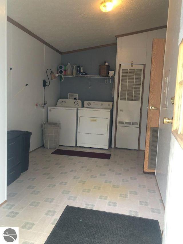 6626 Terry Ln, Hale, MI 48739 - laundry room with crown molding, a heating unit, washing machine and dryer, a textured ceiling, and light floors