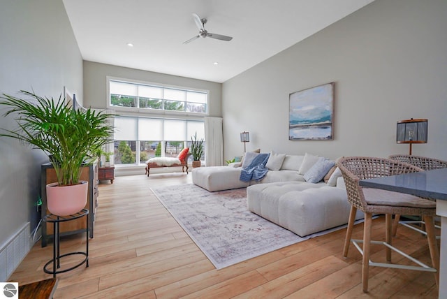 living area featuring a ceiling fan, light wood-type flooring, recessed lighting, and a high ceiling