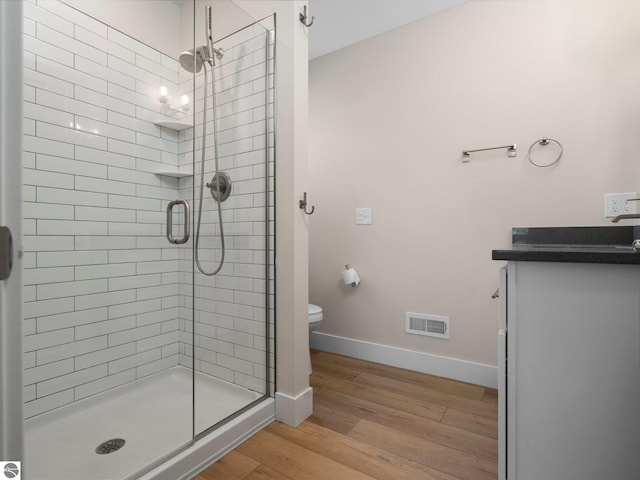 bathroom with a shower stall, wood finished floors, toilet, baseboards, and vanity