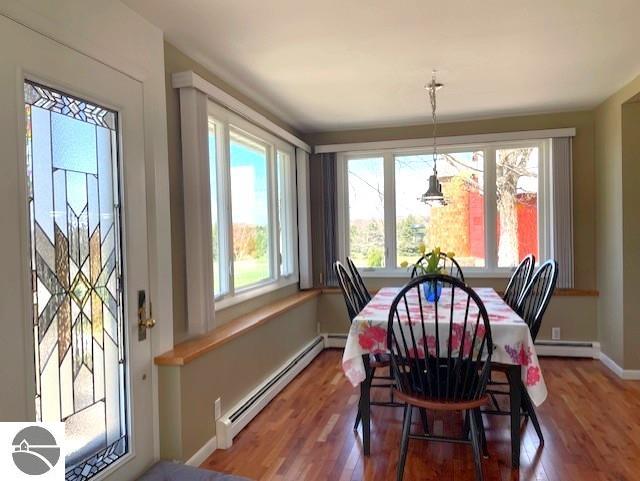 3312 Zimmerman Rd, Traverse City, MI 49685 - dining space featuring a baseboard radiator, wood finished floors, and baseboards