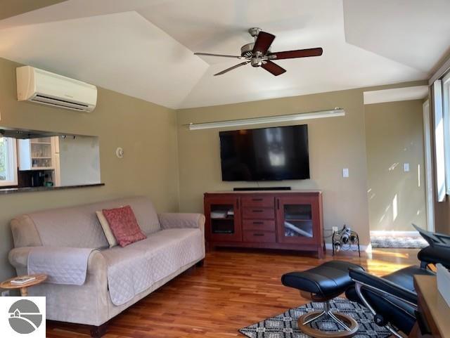3312 Zimmerman Rd, Traverse City, MI 49685 - living room with a wall mounted air conditioner, vaulted ceiling, ceiling fan, and wood finished floors