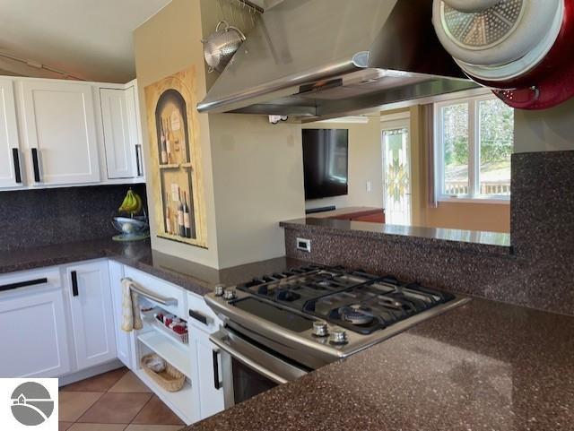 3312 Zimmerman Rd, Traverse City, MI 49685 - kitchen with stainless steel range with gas stovetop, white cabinetry, extractor fan, and dark stone counters