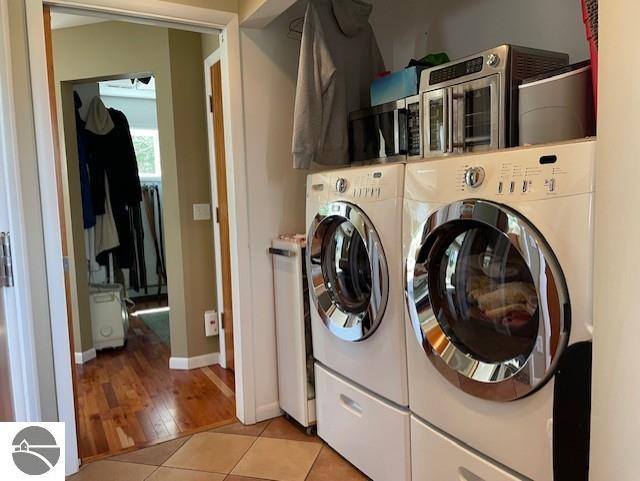 3312 Zimmerman Rd, Traverse City, MI 49685 - washroom featuring washing machine and clothes dryer, light tile patterned floors, and baseboards