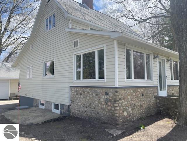 3312 Zimmerman Rd, Traverse City, MI 49685 - view of side of home with a chimney, a garage, and a patio area