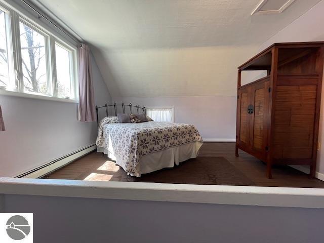 3312 Zimmerman Rd, Traverse City, MI 49685 - bedroom with a baseboard radiator, multiple windows, vaulted ceiling, and baseboards