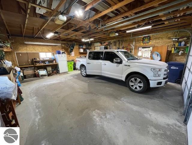 3312 Zimmerman Rd, Traverse City, MI 49685 - garage featuring freestanding refrigerator and a garage door opener