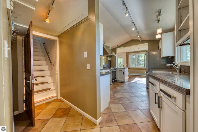3312 Zimmerman Rd, Traverse City, MI 49685 - kitchen with rail lighting, stainless steel gas stove, wall chimney exhaust hood, lofted ceiling, and baseboards