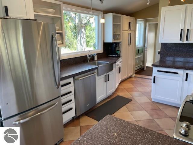 3312 Zimmerman Rd, Traverse City, MI 49685 - kitchen featuring stainless steel appliances, open shelves, tasteful backsplash, white cabinetry, and vaulted ceiling