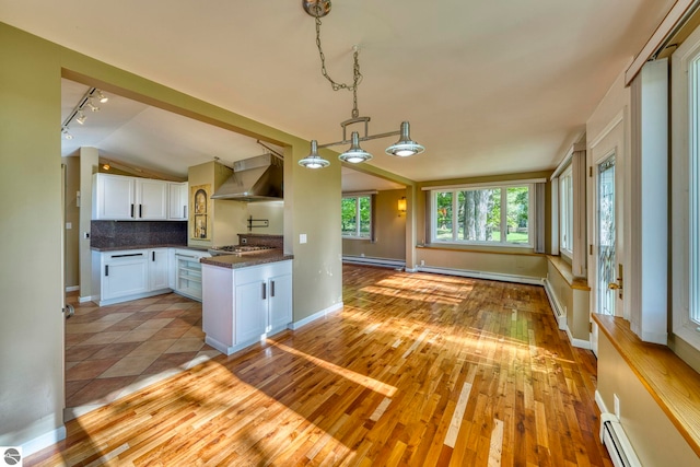 3312 Zimmerman Rd, Traverse City, MI 49685 - kitchen featuring wall chimney range hood, a baseboard heating unit, baseboard heating, track lighting, and dark countertops