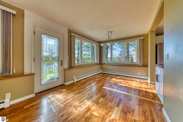 3312 Zimmerman Rd, Traverse City, MI 49685 - unfurnished dining area featuring wood-type flooring, plenty of natural light, baseboards, and a baseboard radiator