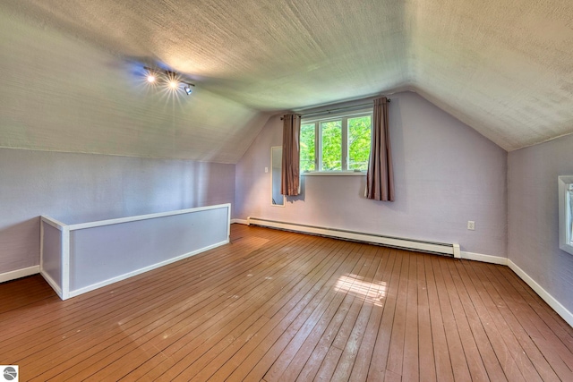 3312 Zimmerman Rd, Traverse City, MI 49685 - additional living space with a baseboard heating unit, baseboards, hardwood / wood-style flooring, lofted ceiling, and a textured ceiling