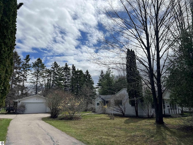 view of front of house featuring an outbuilding, a detached garage, and a front lawn