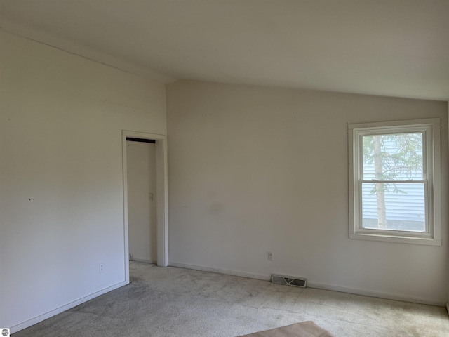 unfurnished room with lofted ceiling, light carpet, and baseboards