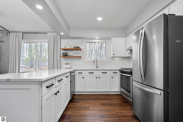 7555 Anthony St, Fife Lake, MI 49633 - kitchen with appliances with stainless steel finishes, a peninsula, tasteful backsplash, white cabinetry, and recessed lighting
